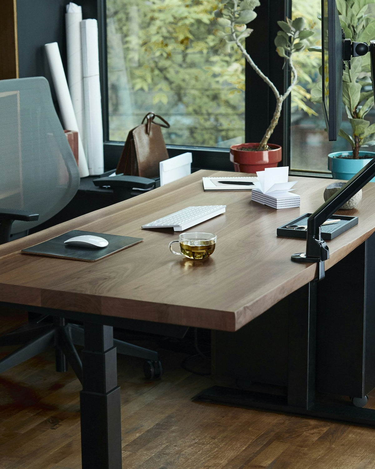 Standing desk with a wooden top in a study with shelves and a large window