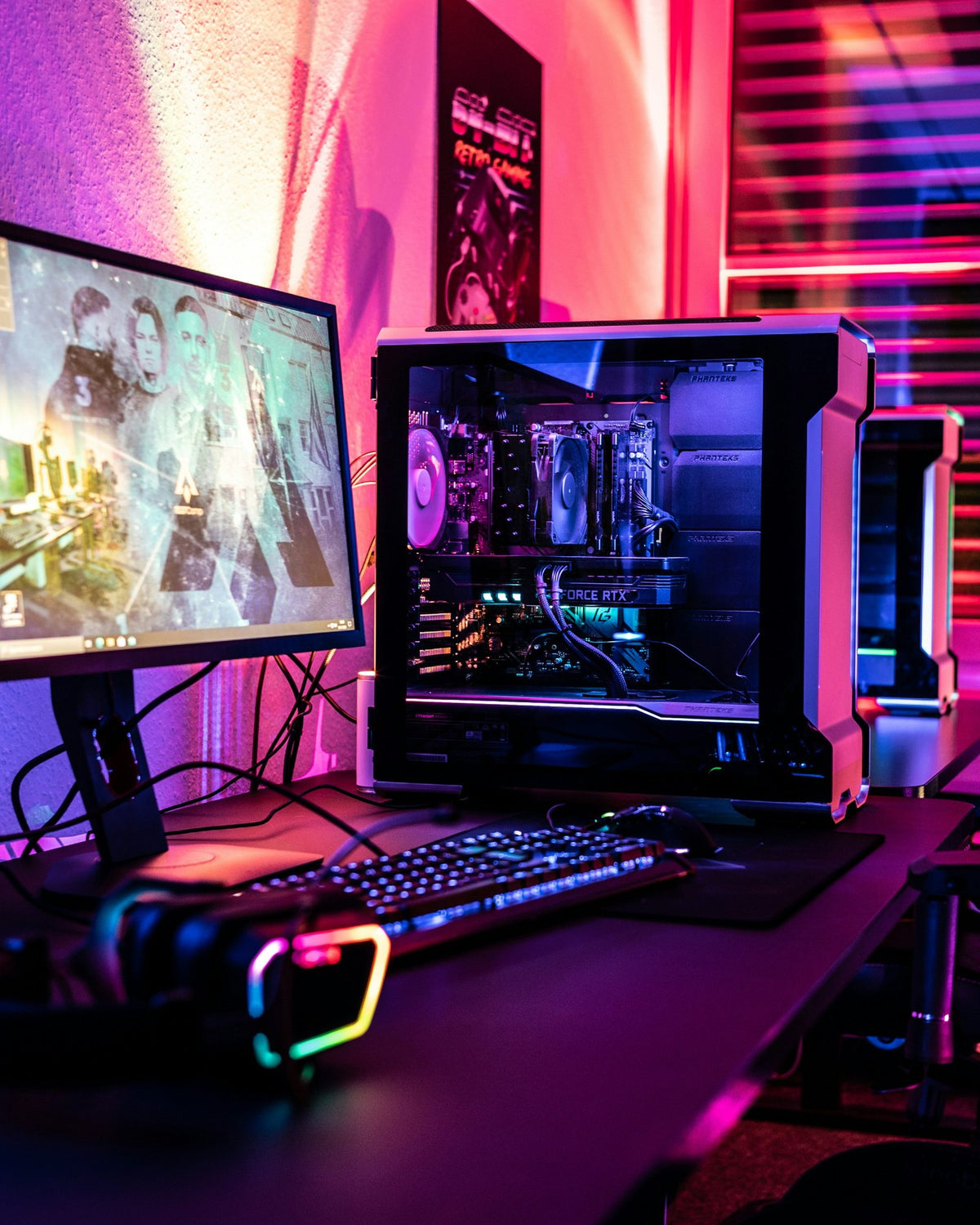 Gaming desk with a monitor, a lit PC and a gaming chair under pink and violet light