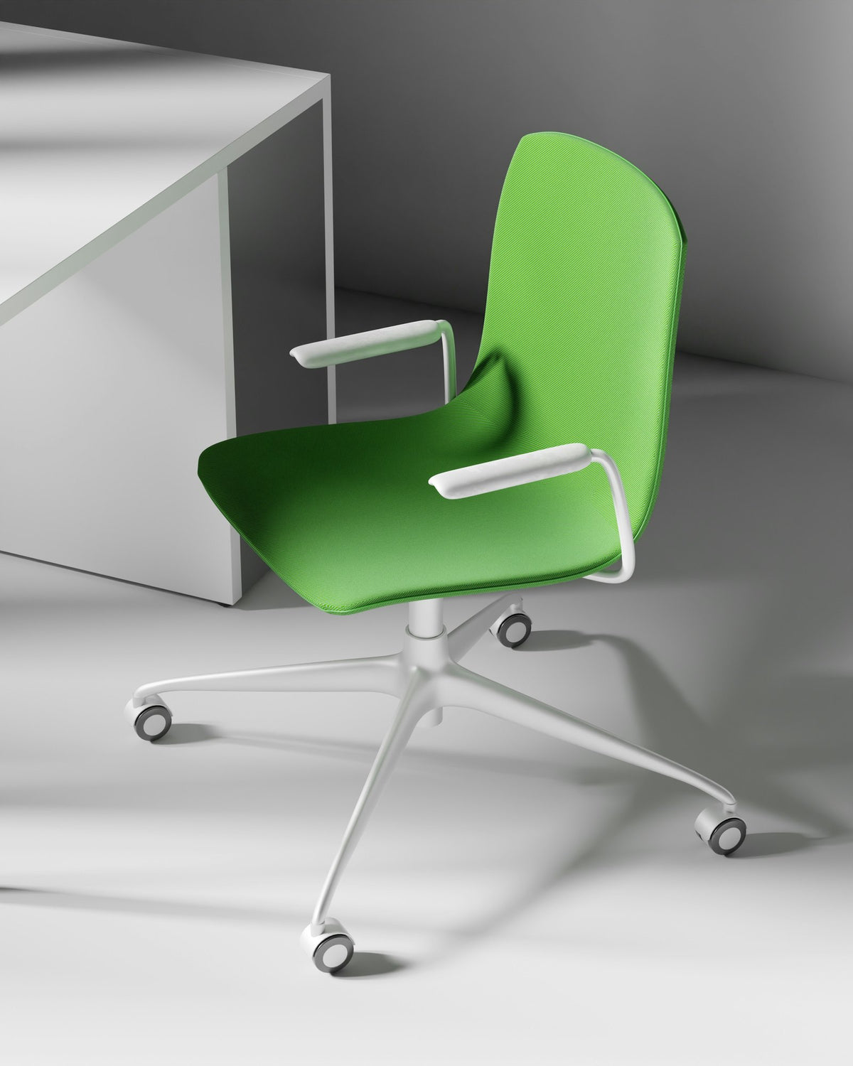 Green task chair beside a white desk in a light grey studio