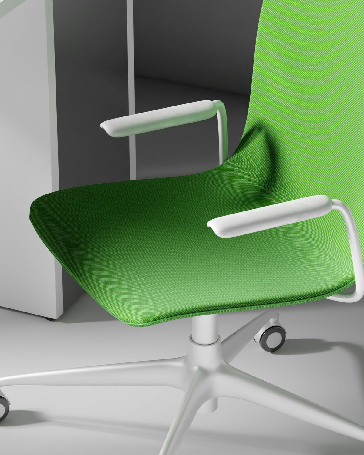 Green task chair beside a white desk in a light grey studio